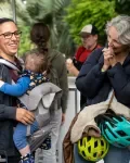 Une femme portant son bébé discute avec une autre femme, les deux sourient. 