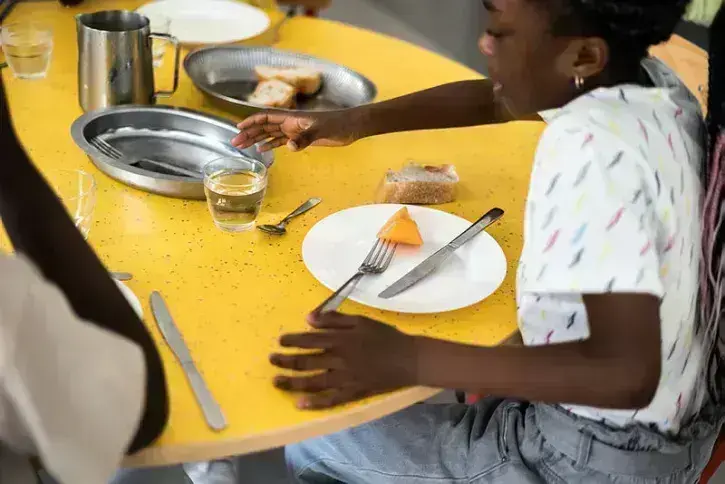 Une jeune fille dans une cantine scolaire prend un verre d'eau. 