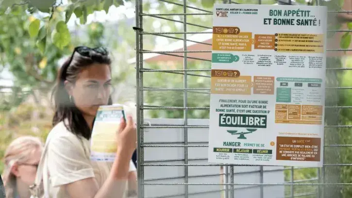 Une habitante devant les panneaux de présentation de la caisse commune de l'alimentation.