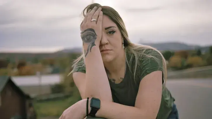 Une femme cache son oeil avec un tatouage en forme d'oeil. 