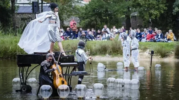 Une artiste et ses musiciens dansent sur un piano sur l'eau.