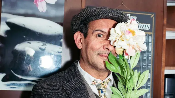 Une photo d'un homme tenant une fleur devant ses yeux. 