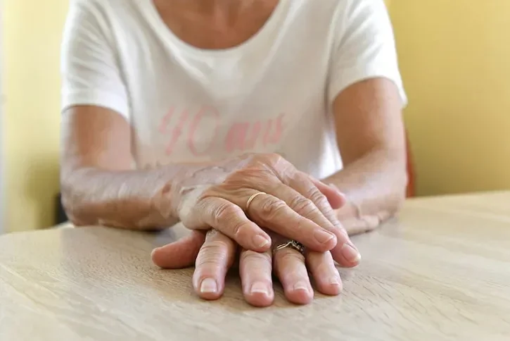 Une personne croise les mains sur une table.
