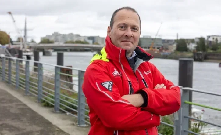 Le pilote de Loire pose avec son manteau rouge sur les quais de la Loire, avec le chantier du pont Anne-de-Bretagne en arrière plan. 