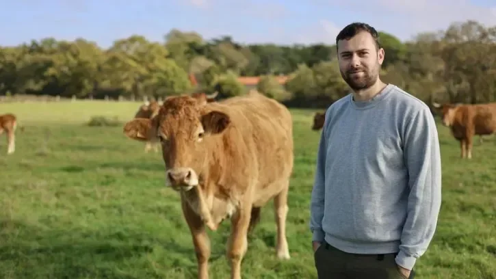 L'éleveur Florian Brossard dans un champ, avec ses vaches de race limousine.