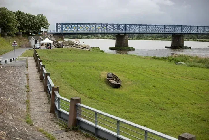 Le pont de Mauves-sur-loire, avec au premier plan un carré d'herbe où se trouve une barque. 