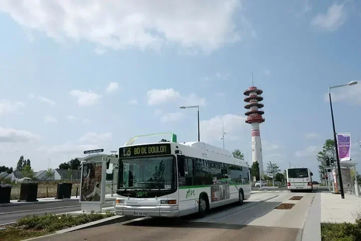 Un chronobus quittant l'arrêt Claude Bernard circule sur une voie de bus propre. En arrière plan, avec la tour hertzienne de Saint-Herblain.