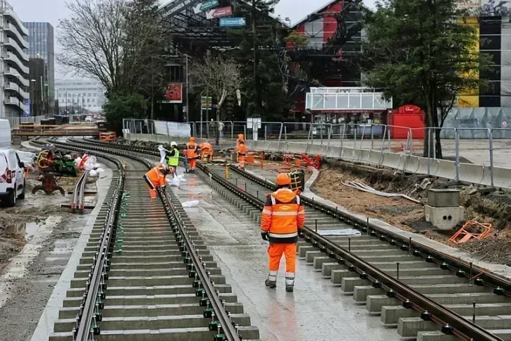 Des équipes travaillent à poser les rails de tramway à côté des Nefs de l'île de Nantes. 