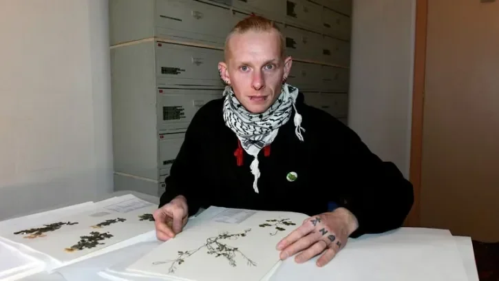 Un botaniste manipule un herbier.