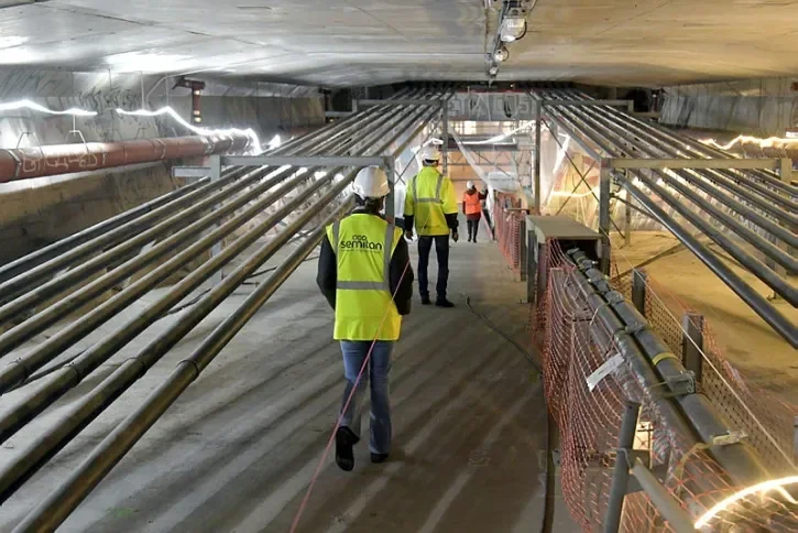 De grands câbles traversent de part et d'autres l'intérieur du caisson du pont des Trois-Continents. Au milieu marchent des personnes équipées de casque de protection et d'un gilet fluorescent floqué Semitan.