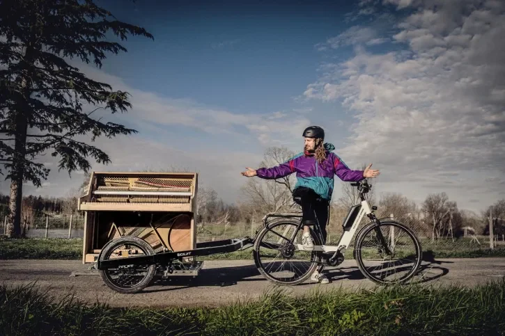 Un homme à vélo tracte un piano.