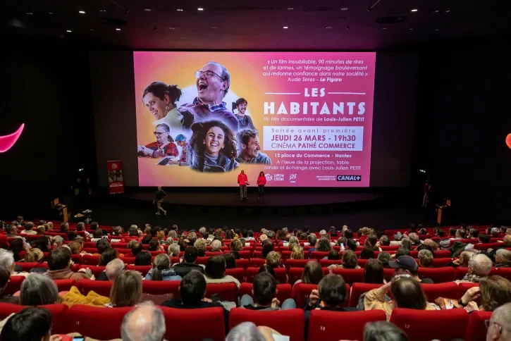 Une salle de cinéma avec des spectateurs, avant une projection. 