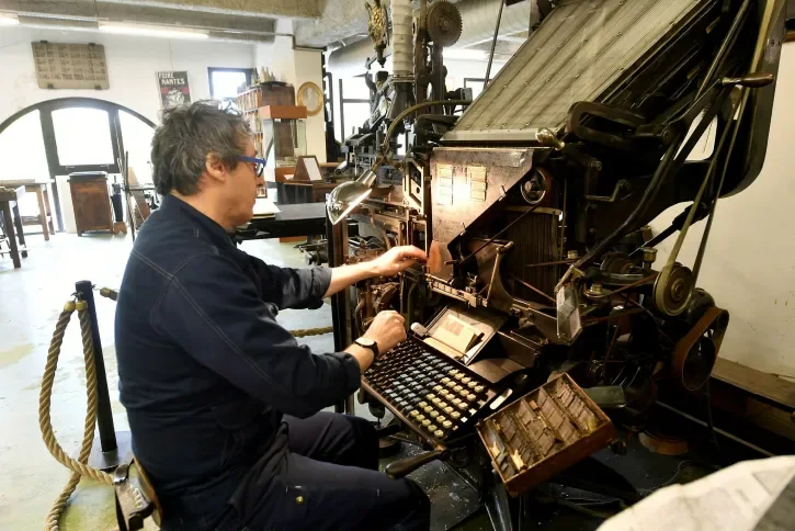 Un ouvrier manipule une presse au Musée de l'imprimerie
