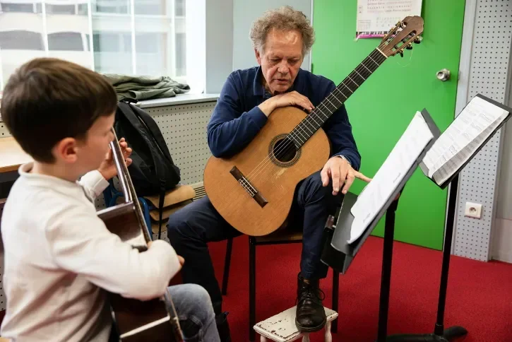 Un jeune garçon apprend la guitare. 