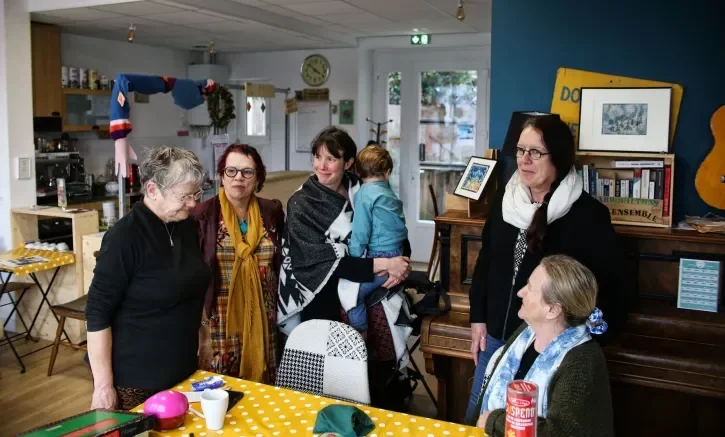 Plusieurs personnes d'âges différents discutent debout autour d'une table.