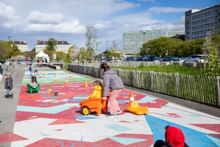 Des enfants jouent sur une grande fresque peinte au sol sur la place de la Petite-Hollande.