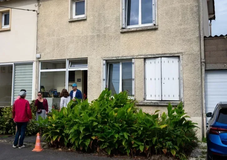 Cinq personnes discutent devant une maison. 