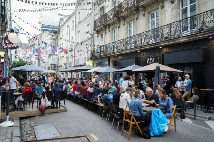 Des gens attablés mangent dans la rue. 