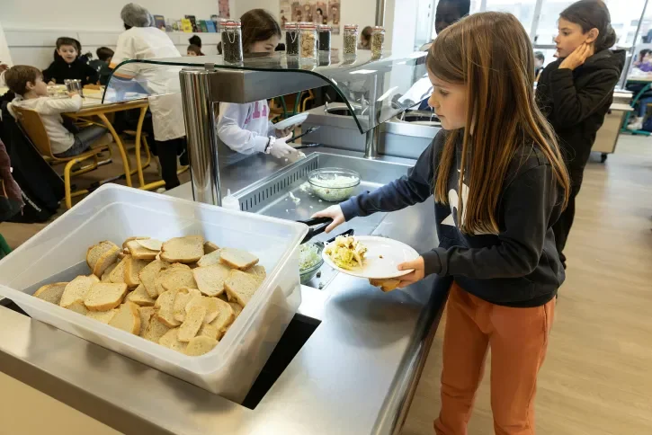 Des enfants se servent à la cantine. 