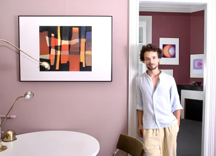Un homme pose devant un tableau.