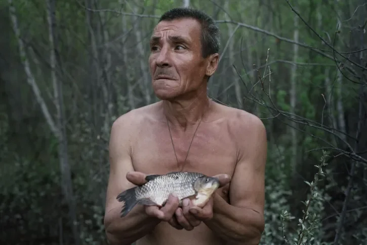 Un homme tenant un poisson mort dans les mains. 