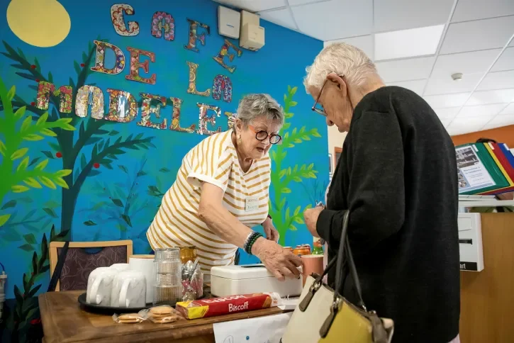 Une personne âgée sert une autre personne. 