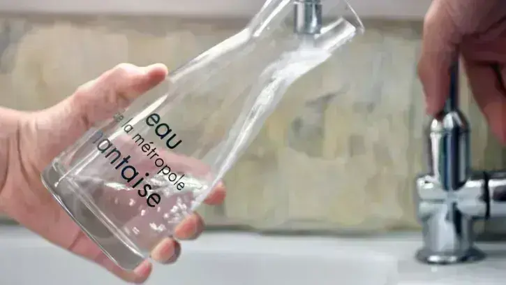 Un habitant de la Métropole remplit une carafe d'eau au robinet